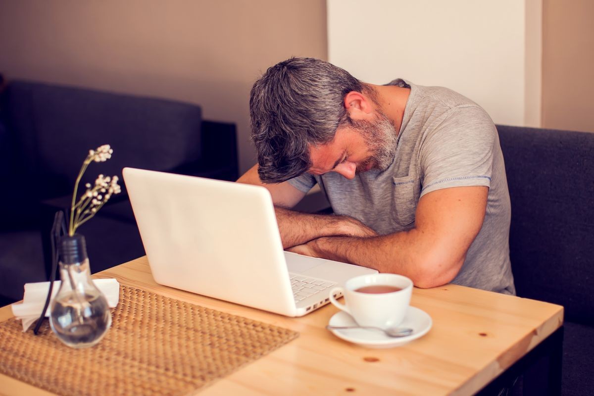 Man having a headache in front of laptop. People, health care and technology concept